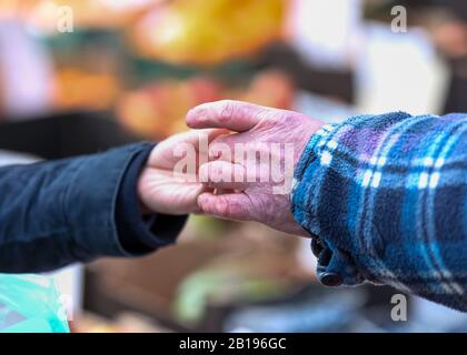 Ein alter Mann, der einer Dame auf einem Sonntagsmarkt in Cardiff, Wales, Früchte überreicht. Stockfoto
