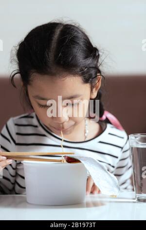 Wenig asiatisches Mädchen am weißen Tisch sitzen, um zu essen, zu instant noodle wählen Sie Fokus geringen Tiefenschärfe eingereicht Stockfoto