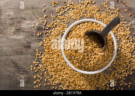 Goldene Flachssamen in weißer Schleife auf Holztisch. Draufsicht. Kopierbereich Stockfoto