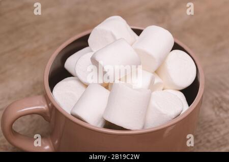 Weißer Marshmallow in großem Becher auf Holzhintergrund Stockfoto