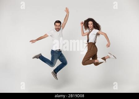 Voller Länge freudiger junger Mann und glückliche Frau, die hoch sprang. Stockfoto