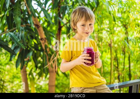 Junge hält Smoothies aus einer Drachenfrucht mit Trinkhalm Stockfoto