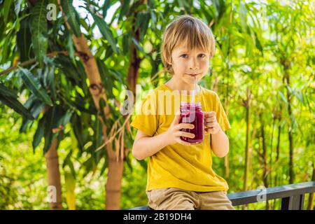 Junge hält Smoothies aus einer Drachenfrucht mit Trinkhalm Stockfoto