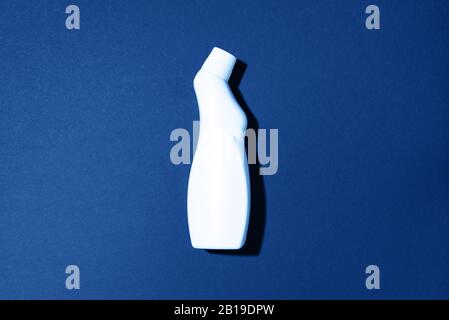 Weiße Kunststoffflasche mit Reinigungsprodukt, Haushaltschemikalien oder flüssigem Waschmittel auf klassischem blauem Hintergrund. Draufsicht. Flaches Lay. Kopierbereich. Waschmittelflasche. Stockfoto