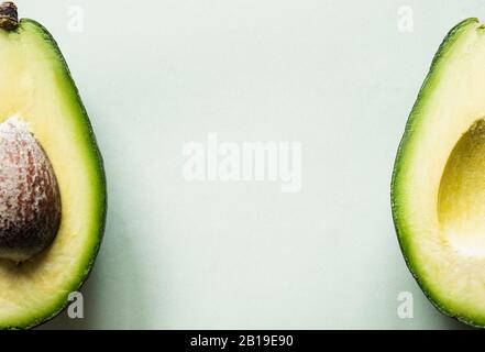 Bereit zum Essen Avocado in zwei Hälften geschnitten, isoliert auf hellgrünem Hintergrund. Stockfoto