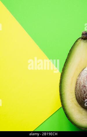 Bereit zum Essen Avocado in zwei Hälften geschnitten, isoliert auf grünem und gelbem Hintergrund. Stockfoto