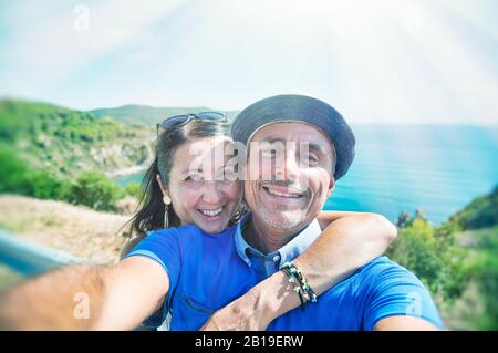 Mann, der Strohhut mit seiner Frau trägt, die sich am Meer erholt, Ozean im Hintergrund. Stockfoto
