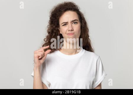 Verärgert junge aufschäumende weibliche Klientin, die winzige Messungen zeigt. Stockfoto