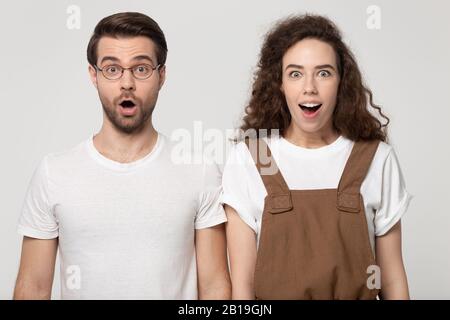 Positiv schockierter Kerl und glückliches Mädchen, das mit dem geöffneten Mund steht. Stockfoto