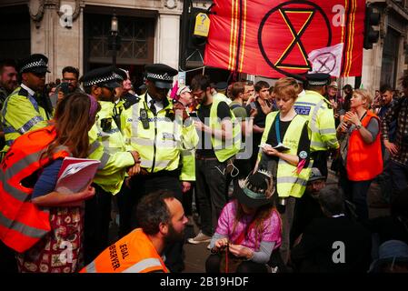 Extinction Rebellion, Occupy London: Ab Montag, 15. April 2019 organisierte Extinction Rebellion Demonstrationen in London, wobei sie ihre Aufmerksamkeit auf Oxford Circus, Marble Arch, Waterloo Bridge und die Gegend um den Parliament Square richtete. Aktivisten fixierten ein rosafarbenes Boot, das nach der ermordeten honduranischen Umweltaktivistin Berta Cáceres in der Mitte der belebten Kreuzung von Oxford Street und Regent Street (Oxford Circus) benannt wurde, und klebten sich darauf und stellten auch mehrere Gazebos, Topfpflanzen und Bäume auf, Eine mobile Bühne und eine Skate-Rampe, während sie auch die Waterloo Bridge besetzen (ref:Wikipedia). Stockfoto