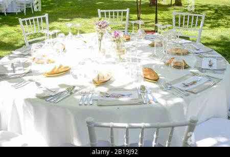 Dekoration und Utensilien auf einem Tisch mit Stühlen für die Feier eines Outdoor-Events vorbereitet. Stockfoto