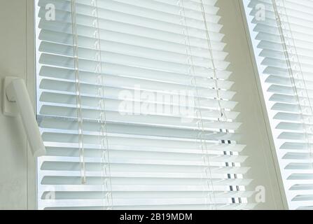 Weißes Kunststofffenster und horizontale Jalousien schließen sich an Stockfoto