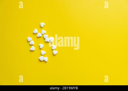 Weiße Kardiologiepillen auf gelbem Hintergrund Minimalismus, Medizinkonzept Stockfoto