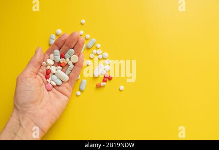 Viele verschiedene Tablettenpillen in der Hand einer Frau auf hellgelbem Hintergrund. Gesundheits- und Medizinkonzept, Kopierraum Stockfoto