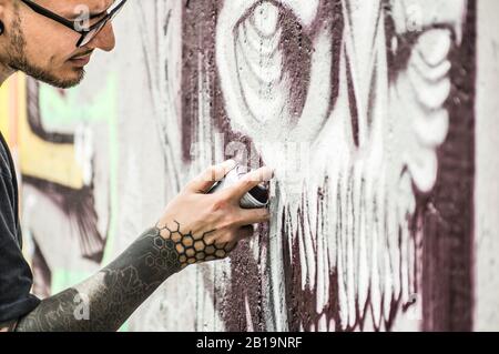 Tätowier-Graffiti-Schriftstellerbemalung mit Farbe sprüht sein dunkles Bild an die Wand - Zeitgenössischer Künstler bei der Arbeit - urbaner Lebensstil, Street-Art-Konzept - Lwl Stockfoto