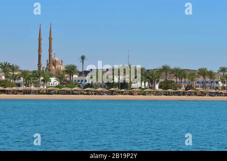 Sonniger Sommer Blick auf den Strand des Roten Meeres mit Moschee im Hintergrund, Sharm El Scheich, Sinai, Ägypten Stockfoto