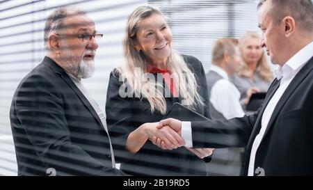 Nahaufnahme: Geschäftsmann und Geschäftsfrau schütteln die Hände in der Bürolobby Stockfoto