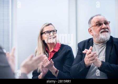 Nahaufnahme: Eine Gruppe von Geschäftsleuten, die während eines Arbeitstreffen applaudieren. Stockfoto