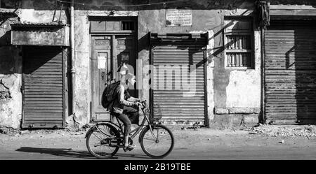 Jamnagar, Gujarat, Indien - Dezember 2018: Eine schwarz-weiße Straßenaufnahme der verschlammten Fenster der Geschäfte in einem Markt, vor dem ein Mädchen befreit Stockfoto