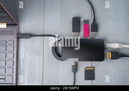 USB-Adapter Typ C oder Hub, der mit verschiedenen Zubehörteilen an den Laptop angeschlossen ist - Pendreifen, hdmi, ethernet, Speicherkarte, Kabel. Flacher Lay Draufsicht. Stockfoto