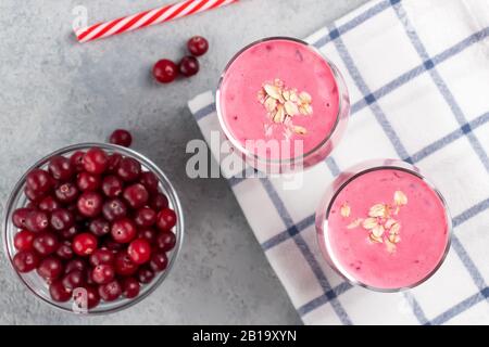 Zwei Gläser mit frisch hausgemachtem Smoothie aus Joghurt, Haferbrei und Preiselbeeren auf einem grauen Tisch. Gesundes Esskonzept. Stockfoto