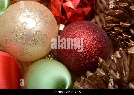 TIS THE SEASON: Weihnachtsschmuck und dekorative Tannenzapfen sitzen in einem Korb. Stockfoto