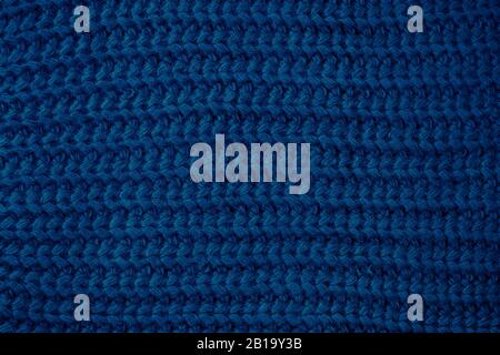 Blau gestrickte Textur, dunkler Stoffhintergrund. Farbe 2020, Trends Mode. Wollpullover, Hintergrundkleidung Stockfoto