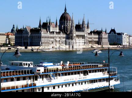 Das ungarische Parlament entlang der Donau. Panoramaaussicht. Großes weißes Kreuzfahrtschiff. Blauer Himmel. Wahrzeichen und berühmte Sehenswürdigkeit. Stockfoto