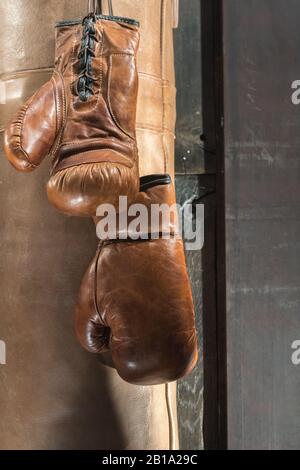 Klassische braune Boxhandschuhe mit Lochtasche und Holzhintergrund Stockfoto
