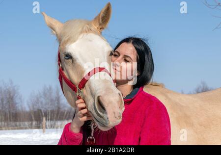 Porträt einer Frau und ihres männlichen palomino-pferdes im Winter Stockfoto