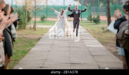 Nahaufnahme: Glückliche Brautpaar, die die Straße der Stadt hinunterlaufen. Stockfoto
