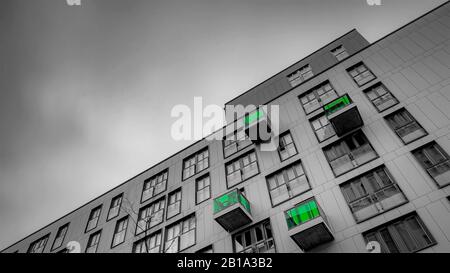 Ein abstraktes Hintergrundbild der Fenster auf einem Wohnblock in der Stadt mit selektiver Farbe auf den Balkonen. Stockfoto