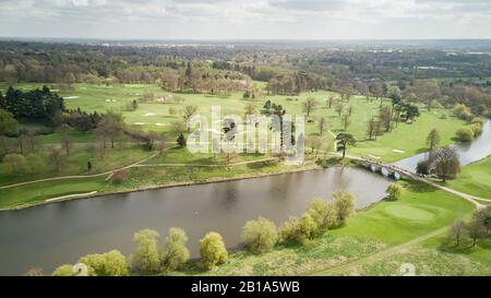 Die südenglische Landschaft an einem hellen Frühlingstag mit einer Steinbrücke, die einen Fluss in Richtung eines Golfplatzes überquert. Luftdronansicht. Stockfoto