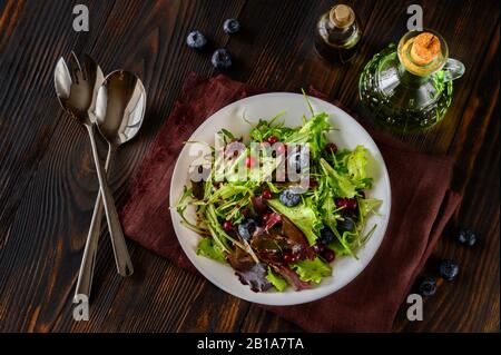 Schüssel mit frischem Salat mit Beeren und Balsamiksoße Stockfoto