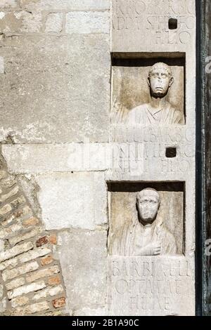 Triest, Italien. 14. Jahrhundert Kathedrale von San Giusto hat viele Stücke der römischen funerary Skulptur, die nach dem Zufallsprinzip in die Fassade integriert Stockfoto