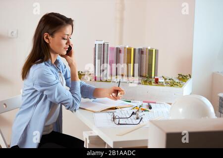Junge hübsche Frau analysiert ein Designobjekt und spricht mit Kunden. Nahansicht Foto. Herstellung, Technik, Nahaufnahme Foto. Kopierraum Stockfoto
