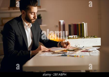 Der junge Mann in stilvoller formeller Kleidung entwickelt die Konzepte für Strukturen und verwandelt diese in Bilder und Pläne.Nahaufnahme Stockfoto