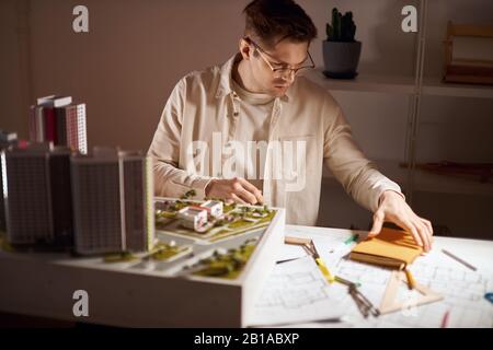 Junger gutaussehender Mann in Brille und weißem Hemd, der sein gelbes Notizbuch nimmt, um einige Notizen zu machen, Nahaufnahme Foto. Kerl, der nützliche Informationen schreiben wird Stockfoto