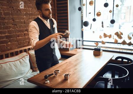 Zubereitung von Kaffee, professioneller Barista mit Portafilter mit gemahlenem Kaffee während der Arbeit in der Café-Bar, Nahansicht Foto Stockfoto