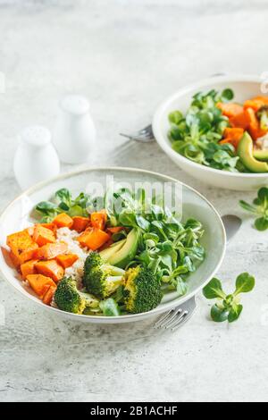 Vegane Mittagsschüssel mit braunem Reis, Brokkoli, Süßkartoffel, Reis und Salat, Kopierraum. Veganes Lebensmittelkonzept. Stockfoto