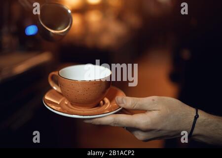 Mann, der eine leere Tasse hält, Mann bittet um Tee oder Kaffee, gebt mir bitte etwas Kaffee. Nahaufnahme eines geschnittenen Fotos, verschwommener Hintergrund Stockfoto