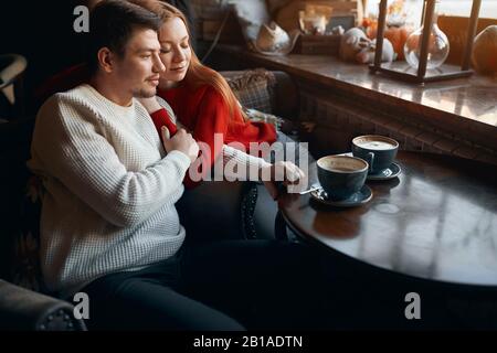 Yong schöne Frau mit geschlossenen Augen auf die Schulter ihres Mannes gelehnt, während sie drinnen Tee trinkt. Nahansicht Foto, beste Zeit mit Familie, Husb Stockfoto