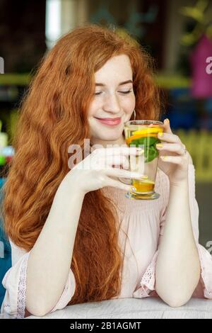 Rothaarige fröhliche Mädchen trinken leckere Mocktails. Konzept für Lifestyle, Getränke und gesunde Ernährung. Stockfoto