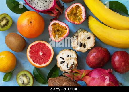 Fruchthintergrund. Verschiedene reife, saftige Exotische asiatische Sommerfrüchte auf blauem Steingrund. Flacher Laienhintergrund in der Draufsicht. Stockfoto