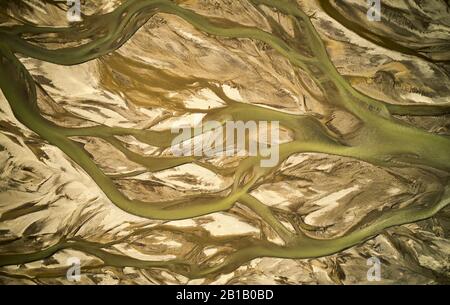 Von oben aus dem Luftbild des kurvenreichen schmutzigen Flusses, der in ariden Flussbetten im isländischen Hochland fließt Stockfoto