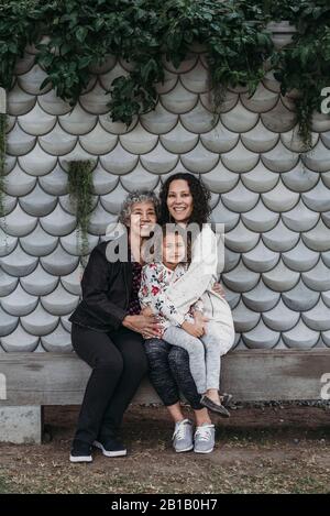 Porträt einer Familie mit mehreren Generationen, die draußen sitzt und lächelt Stockfoto