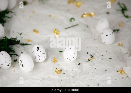 Osterhintergrund. Weiße Eier auf zerknittertem Papierhintergrund mit Moos und goldenen Schabraps. Abstrakte Dekoration, saisonale Anordnung. Stockfoto