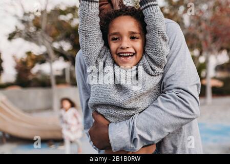 Nahaufnahme von glücklichen Sohn und Vater spielen auf dem Spielplatz in der Dämmerung Stockfoto