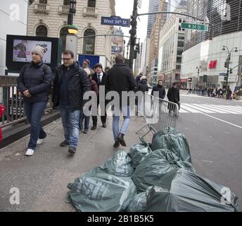 Fußgänger laufen an Müllsäcken an der Bordsteinkante entlang des Broadway an der 34th Street in Manhattan, wo sich Müllabfuhr auf der Straße befindet, da es keine Gassen gibt. Stockfoto