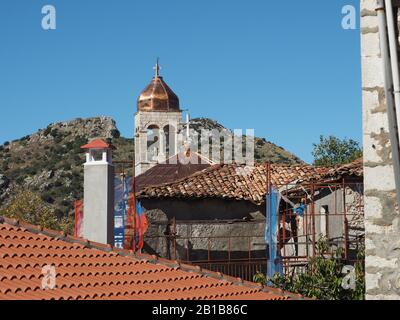 Fliesen- und Kirchturm mit Kupferkuppel und Kreuz in Dimitrana, Arcadia, Peloponnes, Griechenland, gegen einen blauen Himmel. Stockfoto